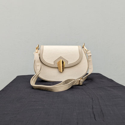 carinno.shop brings you the perfect small beige crossbody bag with a woven-like texture, golden logo-free clasp, golden hardware, and an adjustable strap, placed on a black surface.