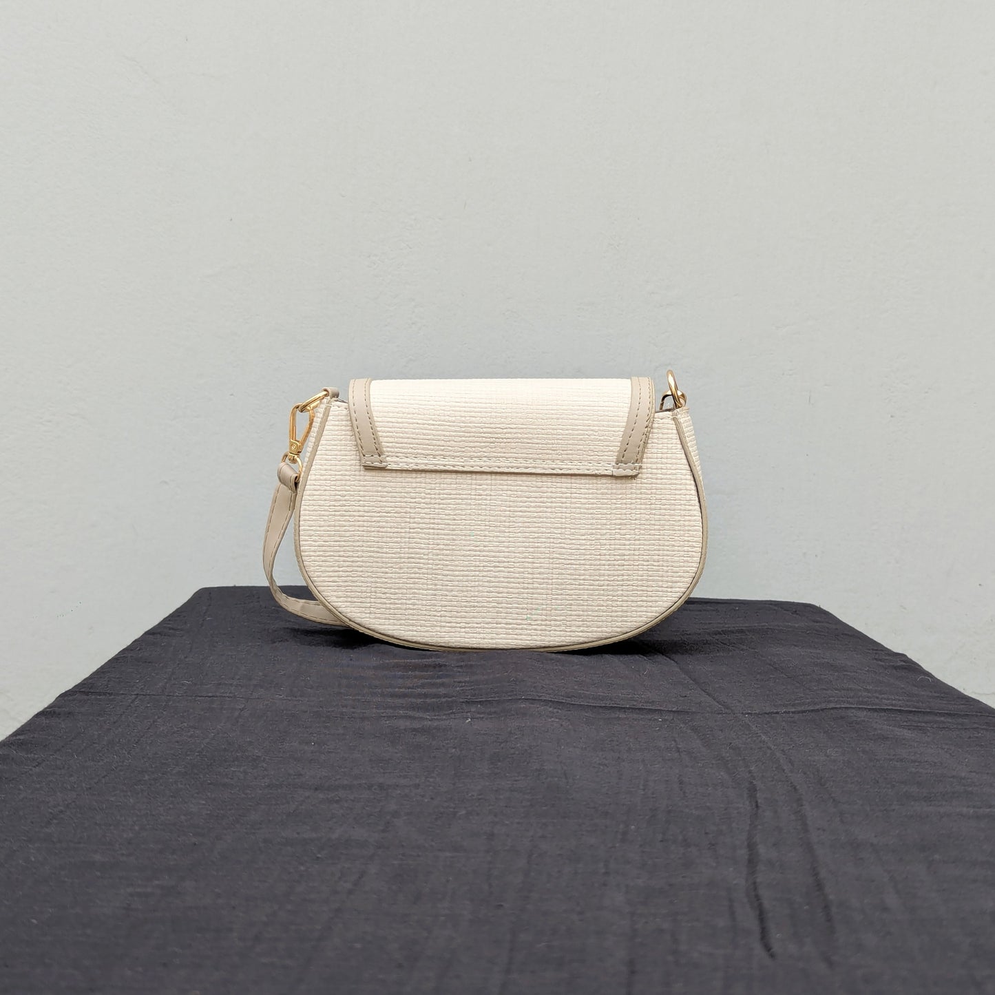 carinno.shop brings you the perfect small beige crossbody bag with a woven-like texture, golden logo-free clasp, golden hardware, and an adjustable strap, placed on a black surface.